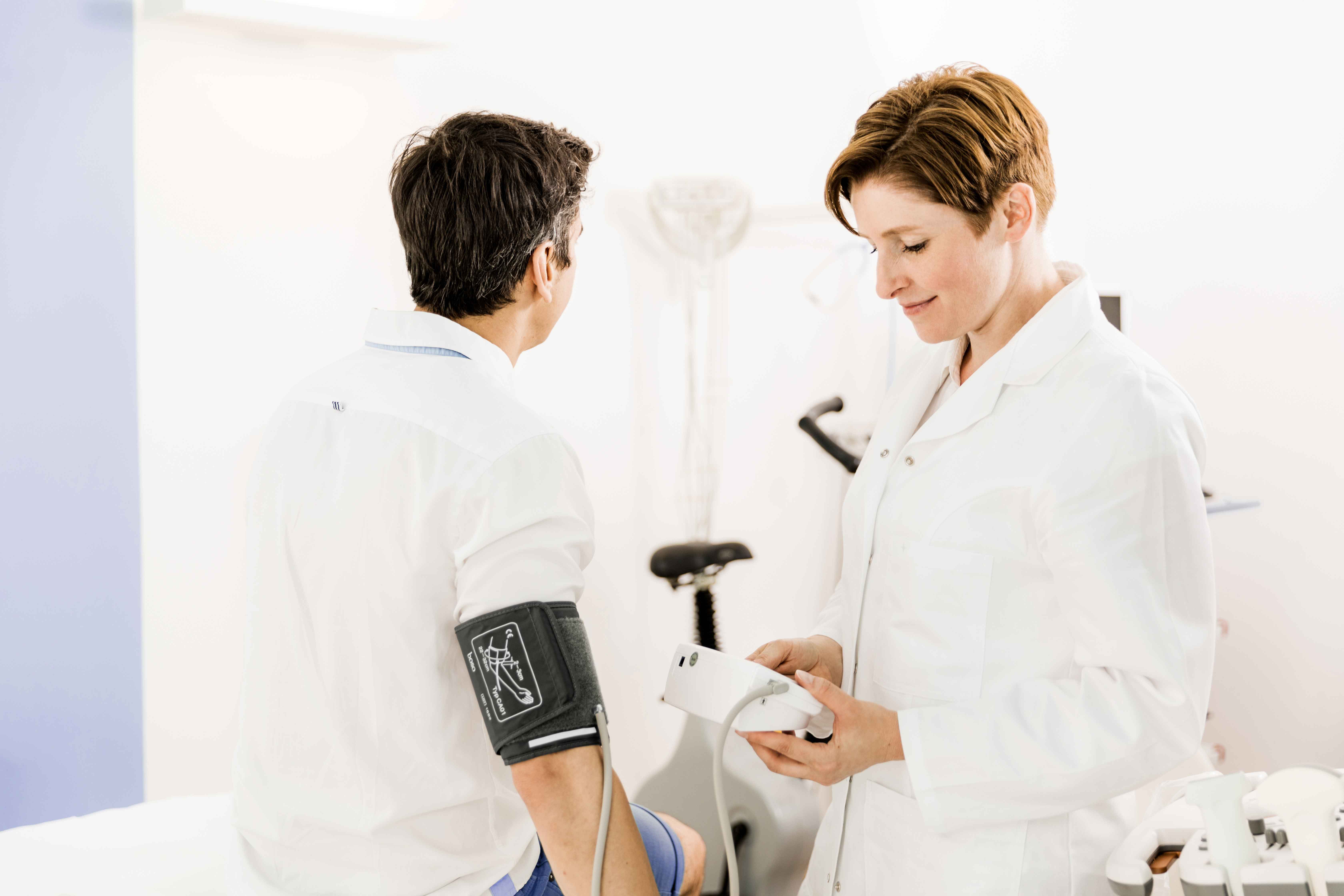 Dr. Manuela Kaus misst den Blutdruck eines Patienten